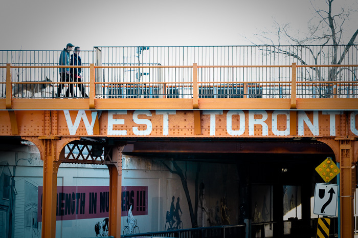 Pedestrians walk along a West Toronto Railpath bridge