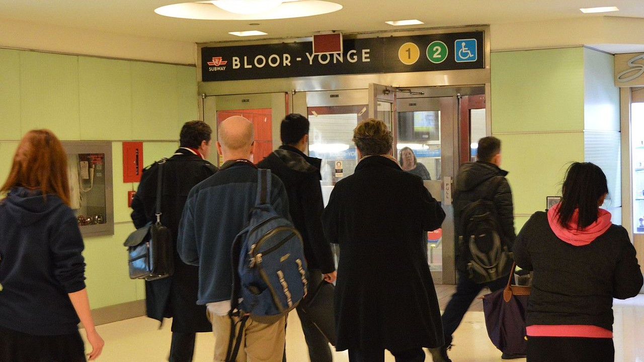An image of multiple people walking in a mall concourse to a Bloor-Yonge subway station entrance