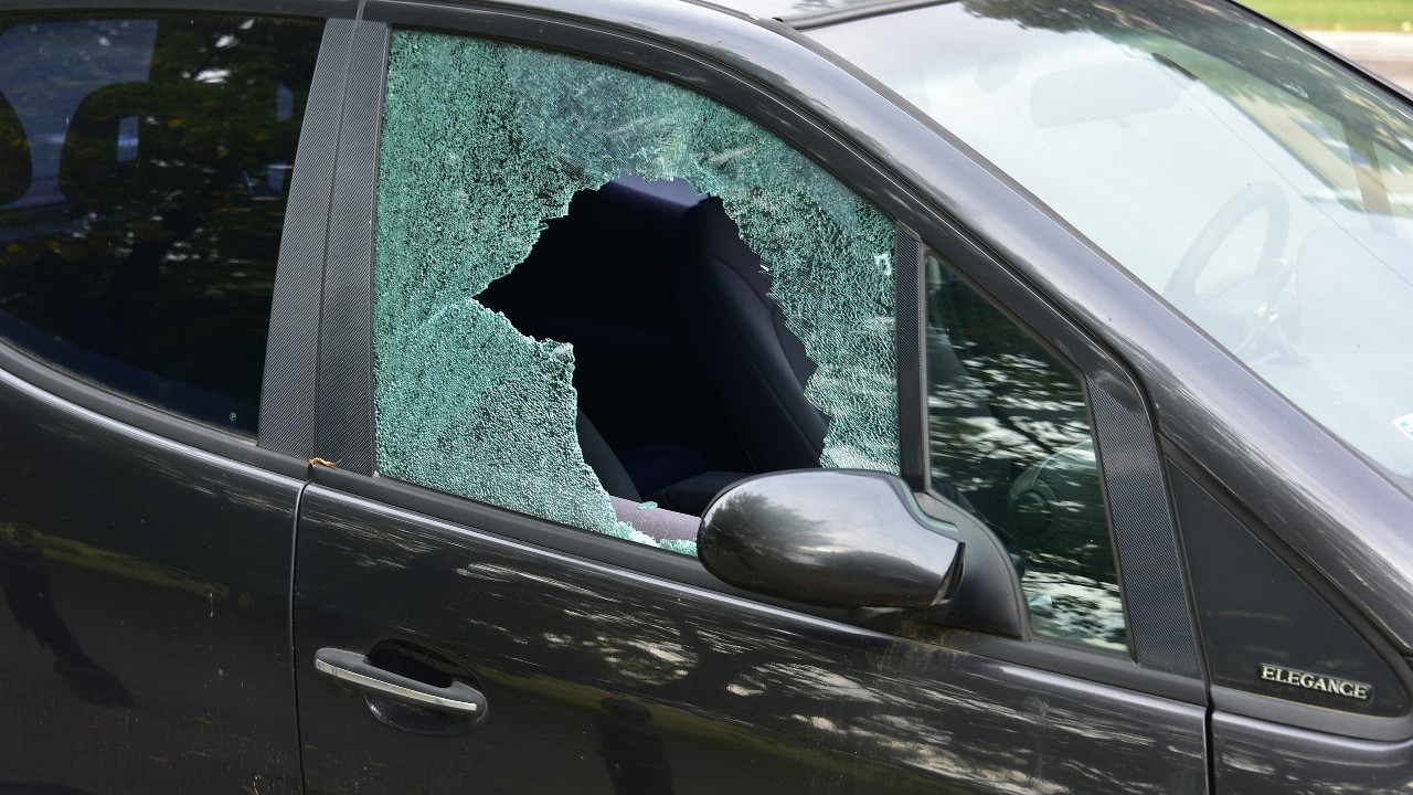 An image of a car with the front passenger-side window smashed in