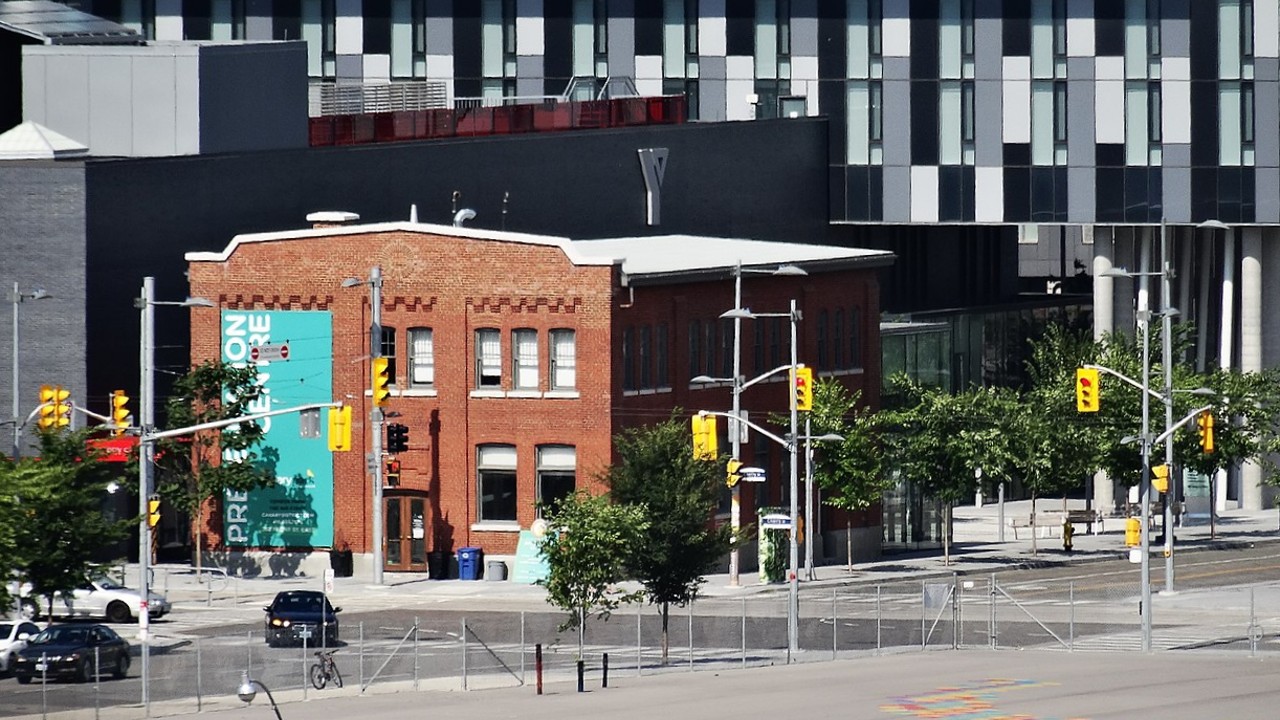 An image of a historic brick building surrounded by new condo buildings in Toronto’s Canary District