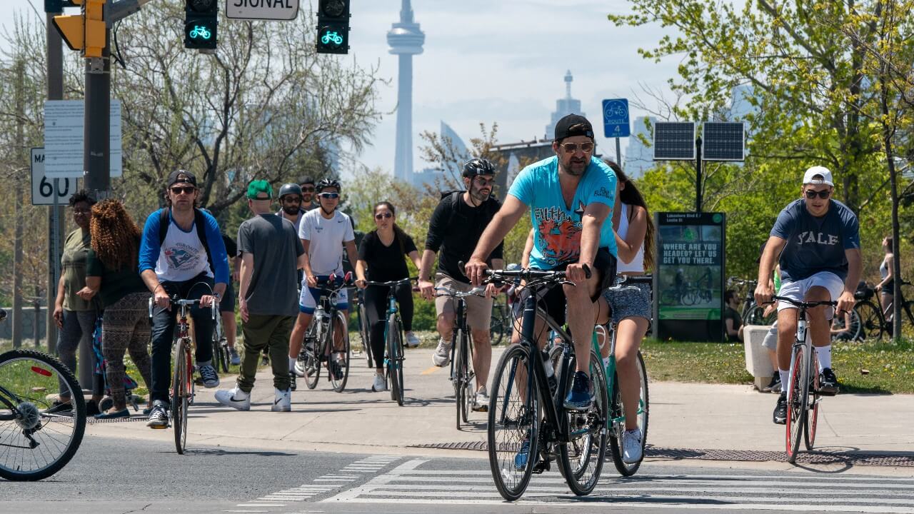 Pedestrians and cyclists travel on a bike path with the CN Tower in the background