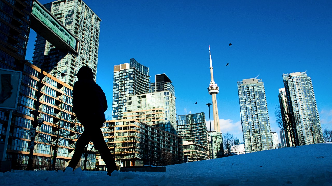 A view of the Toronto skyline in winter with a silhouetted figure walking in the foreground